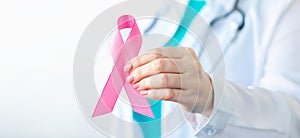 Breast Cancer Awareness Month. Female doctor in medical white uniform holds pink ribbon in her hands. Women& x27;s health