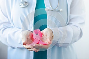 Breast Cancer Awareness Month. Female doctor in medical white uniform holds pink ribbon in her hands. Women& x27;s health