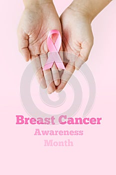 Breast Cancer Awareness Month. A woman& x27;s hands hold pink ribbon on pink background. International symbol of Breast