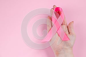 Breast Cancer Awareness Month. Womans hand holds pink ribbon. Health care concept, cancer control symbol.