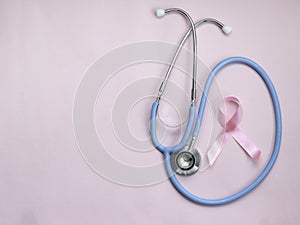 Breast cancer awareness pink ribbon with doctor stethoscope on pink background, october symbol, healthcare and medicine concept