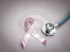 Breast cancer awareness pink ribbon with doctor stethoscope on pink background, october symbol, healthcare and medicine concept