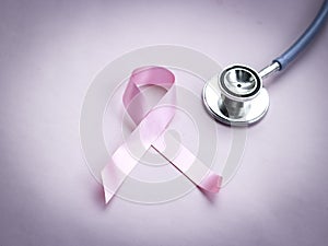 Breast cancer awareness pink ribbon with doctor stethoscope on pink background, october symbol, healthcare and medicine concept