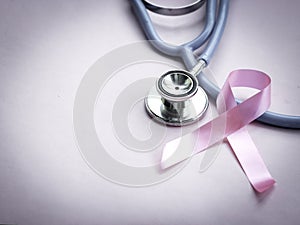 Breast cancer awareness pink ribbon with doctor stethoscope on pink background, october symbol, healthcare and medicine concept