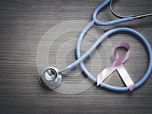 Breast cancer awareness pink ribbon with doctor stethoscope on wooden background, october symbol, healthcare and medicine concept