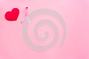 Breast cancer. Mammalogy concept. Symbolic pink ribbon near heart sign on pink background top view copy space