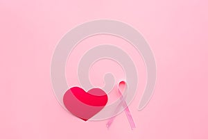 Breast cancer. Mammalogy concept. Symbolic pink ribbon near heart sign on pink background top view copy space