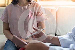 Breast cancer pink awareness ribbon wear on woman patient consulting with doctor who diagnostic examining