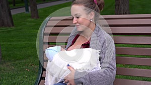 Breast feeding Mother breastfeeds baby boy child city park sitting bench summer day happy smiling