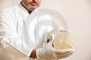 Closeup of breast implant in plastic surgeon hands. Concept of plastic surgery and breast augmentation