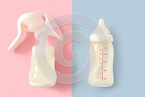 Breast pump and bottle of milk for newborn baby over pink and blue pastel colors background. Maternity and baby care concept. Girl