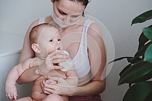 Breastfeeding baby eating milk from mother`s breast and bottle. Concept - breastfeeding and motherhood