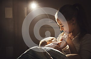 Breastfeeding. mother feeding baby breast in bed dark night