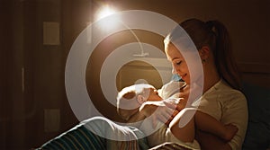 Breastfeeding. mother feeding baby breast in bed dark night photo