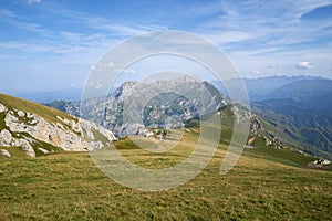 WALLPAPER Sunny summer day in the mouintains Green fields in front of great mountain peak Massive rocks with blue sky and clouds photo