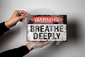 Breathe Deeply. Warning sign with text on a white background in a woman& x27;s hand