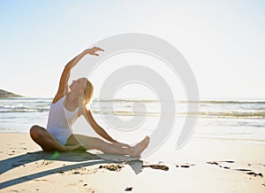 Breathe through the stretches. Full length shot of an attractive young woman doing a yoga stretch early in the morning