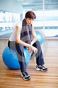 Breather time. Full length of woman sitting on exercise ball and taking a breather. photo