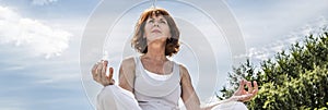 Beautiful middle aged woman sitting in yoga lotus position, banner