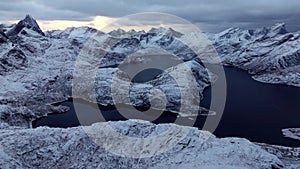 A breathtaking aerial panorama captures snowcapped, rocky mountains in the grip of fierce winds beneath cloudy skies.