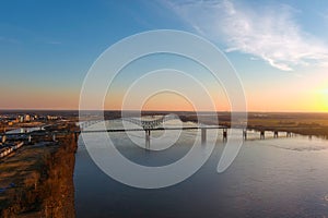 A breathtaking aerial shot of the running waters of the Mississippi river with powerful clouds and a stunning sunset with a bridge