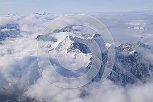 Beautiful aerial view of snow capped mountain peaks above clouds
