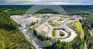 Breathtaking Aerial View of Endless Scandinavian green pine tree forest up to horizon line, full speedway training track below.