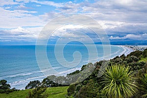 Breathtaking aerial view over vast ocean beach surrounded by distant mountains. Mist rising over water. Patches of blue