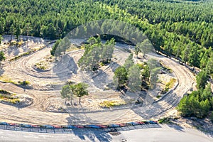 Breathtaking Aerial view of part of speedway training track and Scandinavian green pine tree forest around. Sunny summer day.