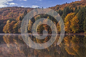 Breathtaking Autumn landscape with colorful forest and its reflection in Trei Ape Lake, Banat, Caras-Severin,Romania