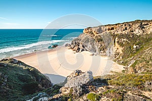 Breathtaking cliffs surround the sandy beach of Praia da Angra da Cerva on the Atlantic coast near Vila Nova de Milfontes, Odemira photo