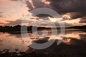 Breathtaking dark sunset cloudscape and its reflection in the river