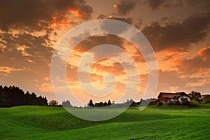 Breathtaking lansdcape of Austrian countryside on sunset. Dramatic sky over idyllic green fields of Anstrian Central Alps on autum