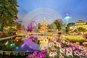 Breathtaking magical landscape in Tivoli Gardens in the evening with lake and flowers. Copenhagen, Denmark. Exotic amazing places