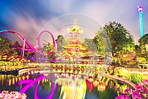 Breathtaking magical landscape in Tivoli Gardens in the evening with rides in the illuminations. Copenhagen, Denmark. Exotic