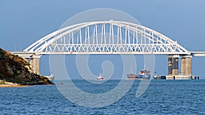 Breathtaking seascape with a white beautiful bridge with many moving cars above the water surface and sailing ships