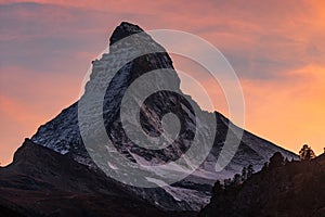 Breathtaking shot of the snow-capped rocky mountain peak under a scenic sunset