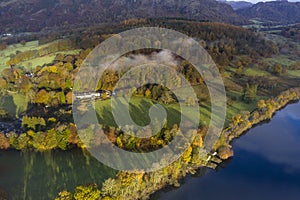 Breathtaking vibrant aerial drone landscape images over Coniston Water at sunrise on beautiful Autumn Fall morning