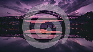 A breathtaking view of a bridge enveloped in a purpletinted sky reflecting its graceful curves onto a calm river below