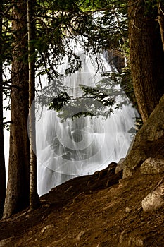 Breathtaking view of a majestic waterfall cascading down a rugged cliff with trees in the foreground