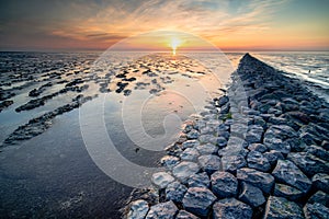 Breathtaking view of mudflat of the Waddenzee during low tide under amazing sunset sky with clouds