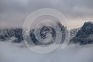 Breathtaking view of rocky snowcap mountains covered in fog