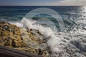 Breathtaking view of splashing sea waves under the sunlight in Varazze, Italy