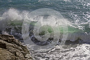 Breathtaking view of splashing sea waves under the sunlight in Varazze, Italy