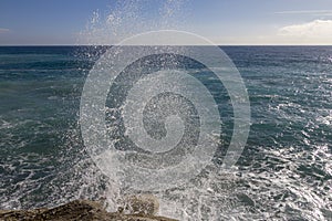 Breathtaking view of splashing sea waves under the sunlight in Varazze, Italy