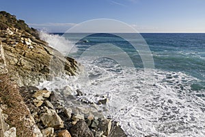 Breathtaking view of splashing sea waves under the sunlight in Varazze, Italy