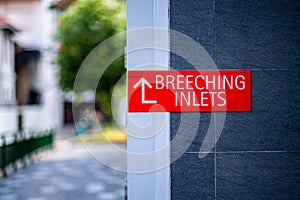 'BREECHING INLET' sign on red plate on concrete wall in Singapore photo