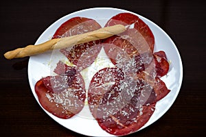 Bresaola, an Italian dish of raw beef cured by salting and air-drying, served typically in slices with a dressing of olive oil, le