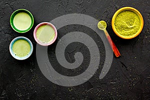 Brew matcha tea. Bowl with powder and cups with beverage on black background top view copy space