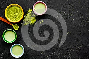 Brew matcha tea. Bowl with powder and cups with beverage on black background top view copy space